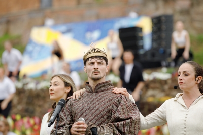 man standing with a mercian flag behind him, wearing a crown 