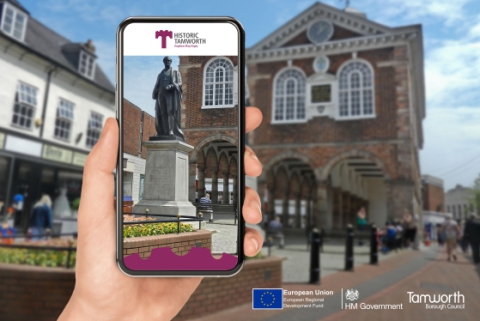 A mobile phone in front of the town hall showing the reality trail app