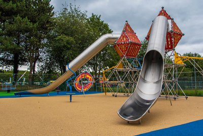A playground with climbing frame and two metal slides