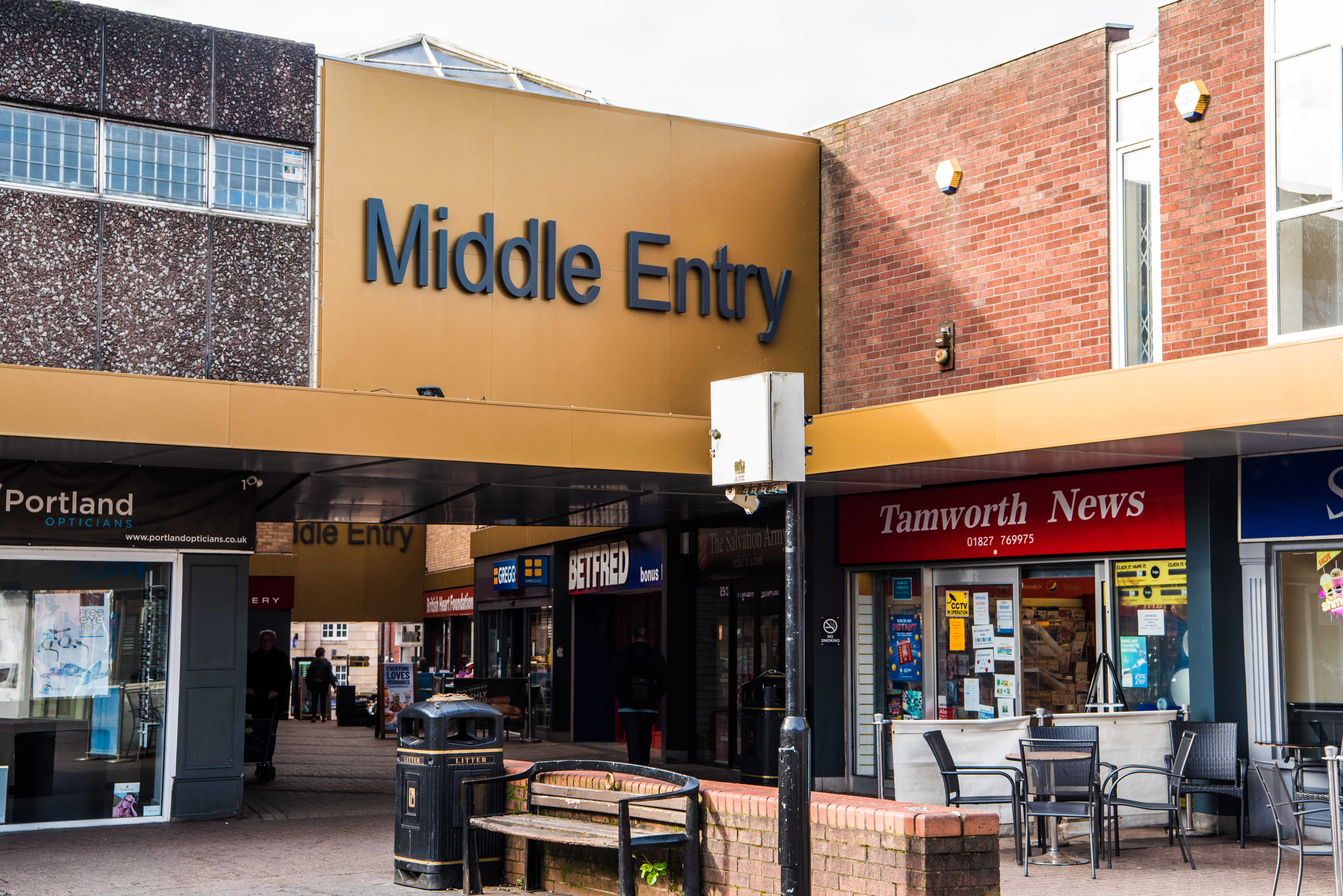 Shops and buildings with a golden bridge with the words 'Middle Entry' on it.