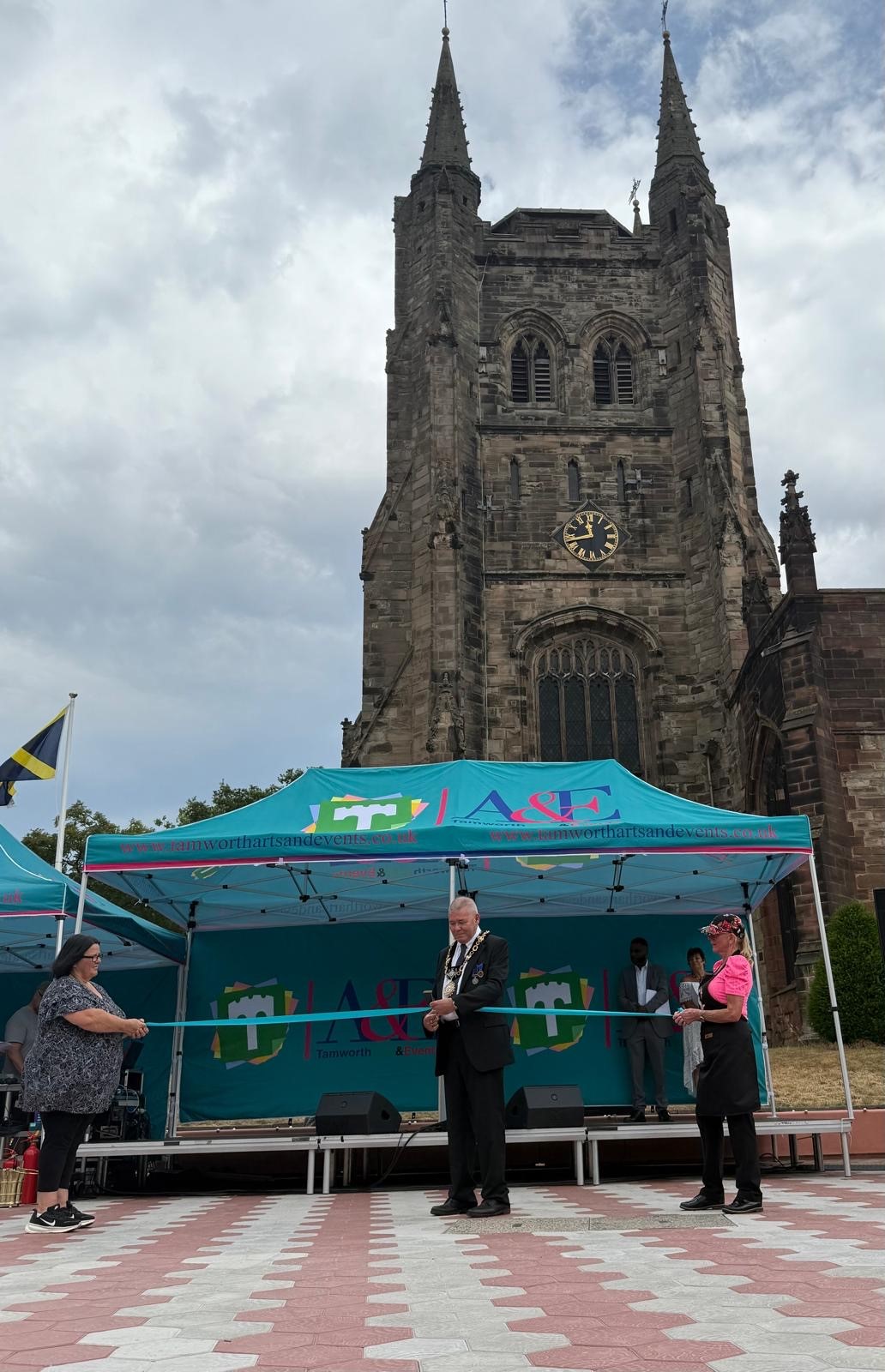 photo of a church with a blue gazebo in front of it and a mayor cutting a blue ribbon