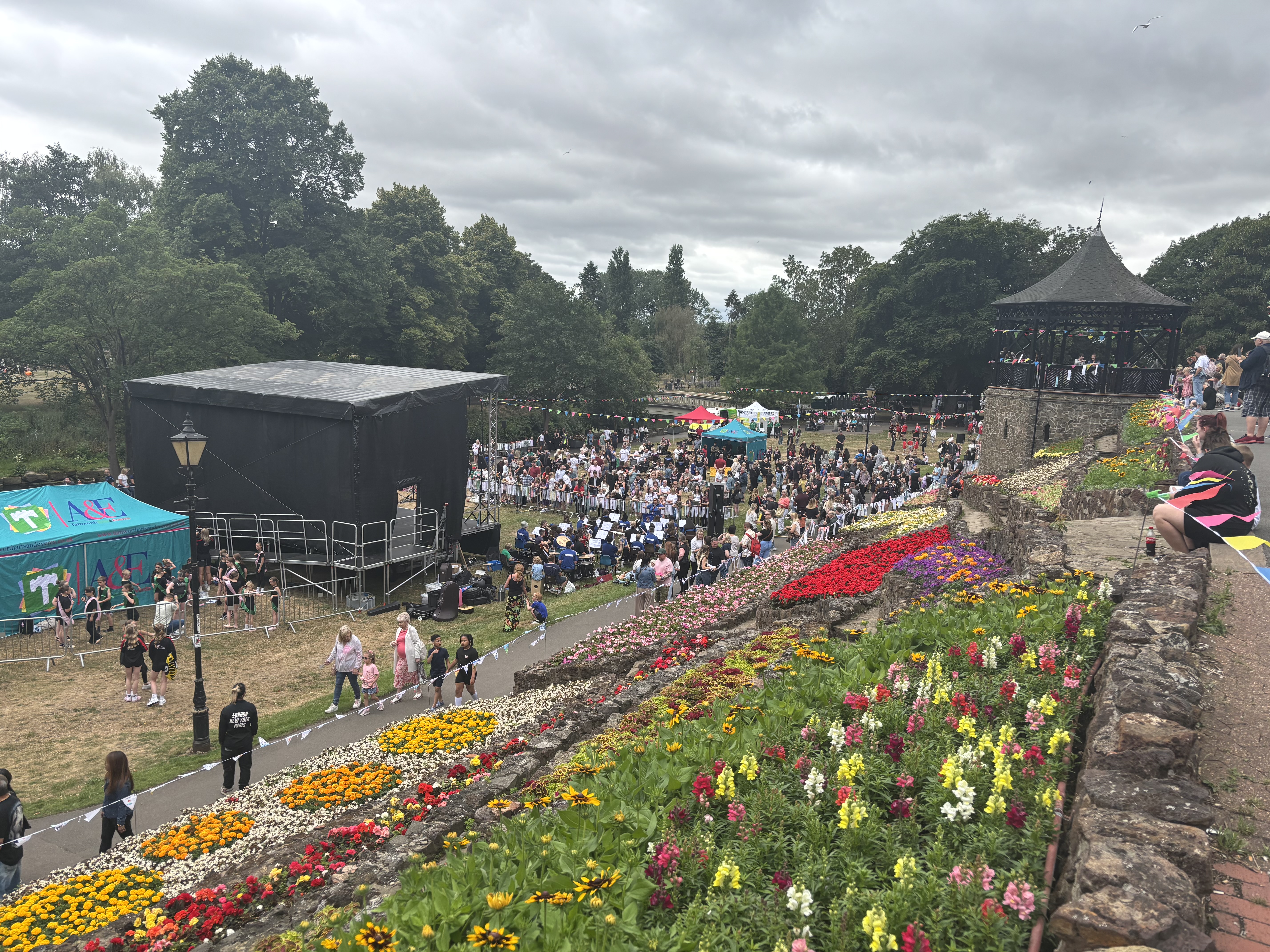 photo of a stage and gazebo on the lower lawn of Tamworth Castle Grounds with crowds of people