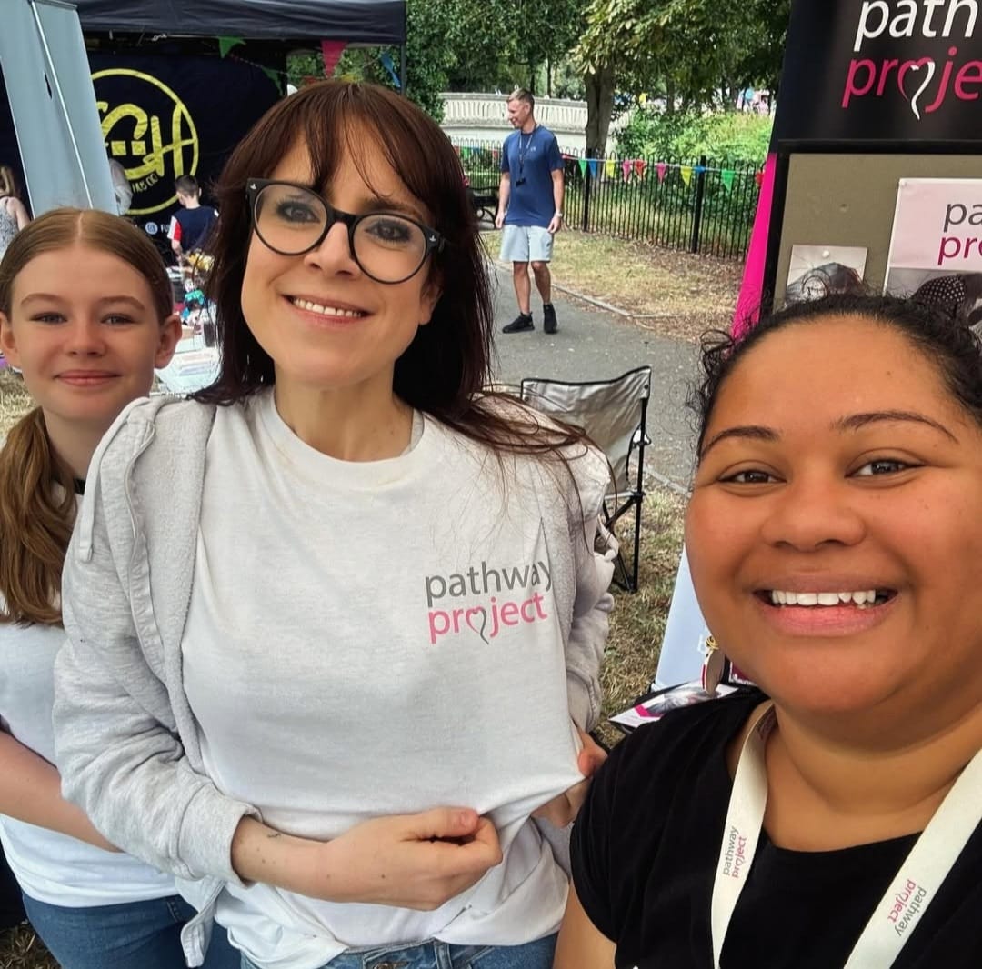 three smiling people outside by pop up banners