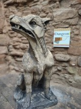 clay statue of a griffin with a castle wall behind.