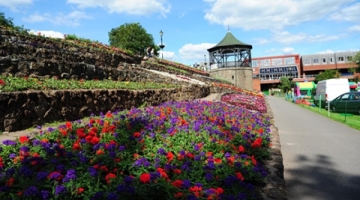 The bandstand behind some red and purple flowers