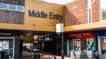 Shops and buildings with a golden bridge with the words 'Middle Entry' on it.