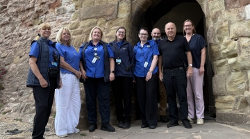 group of people standing outside a brick archway wearing blue top uniform