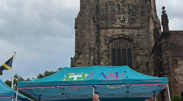 photo of a church with a blue gazebo in front of it and a mayor cutting a blue ribbon