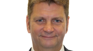 A corporate headshot of a man in a suit